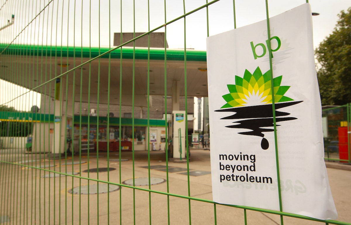 A Greenpeace poster displays a leaking oil logo on a fence after activists closed a BP petrol station in London, England in 2010