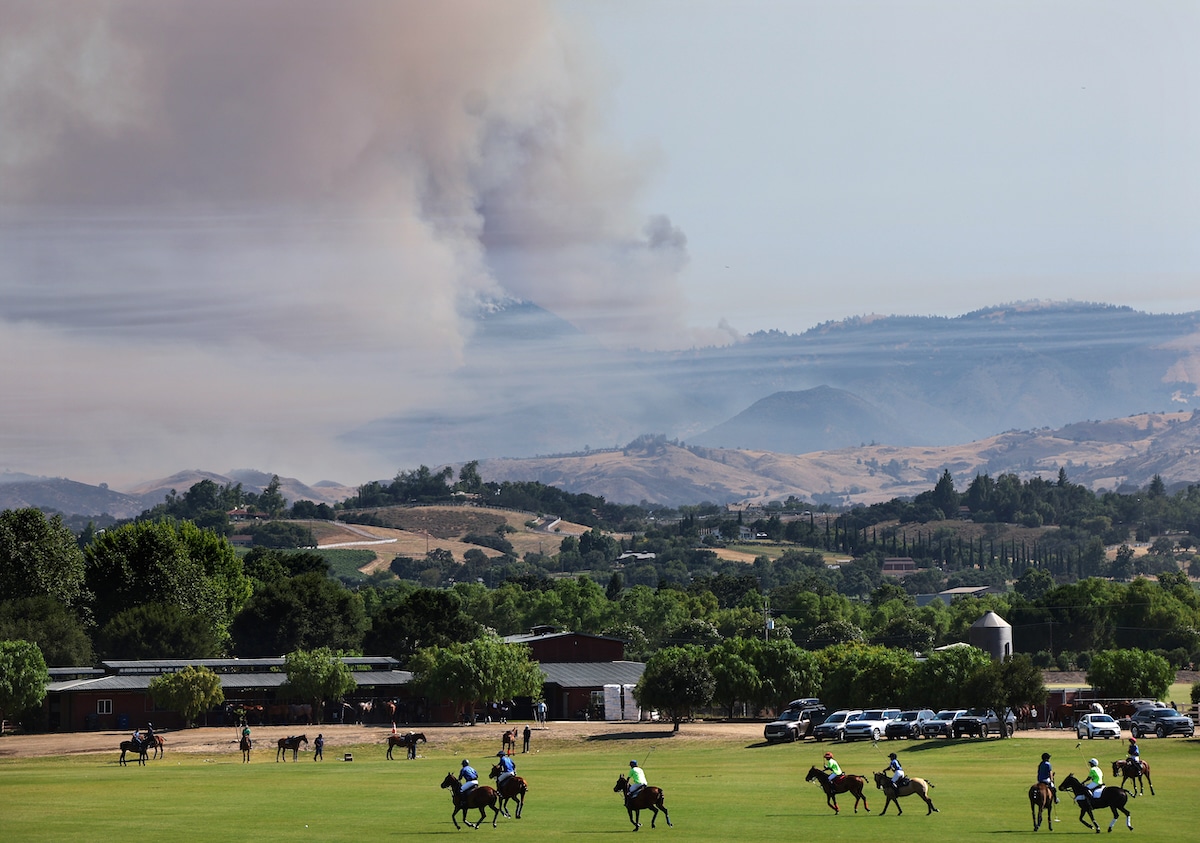 People play polo as the Lake Fire burns in Los Padres National Forest near Los Olivos, California