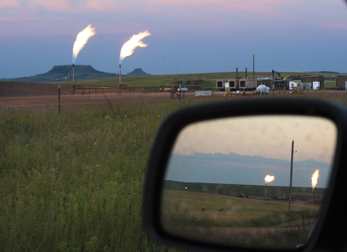 Flaring at oil wells from the burning of natural gas, seen from the road and in a car's side-view mirror in the Fort Berthold Indian Reservation near New Town, North Dakota