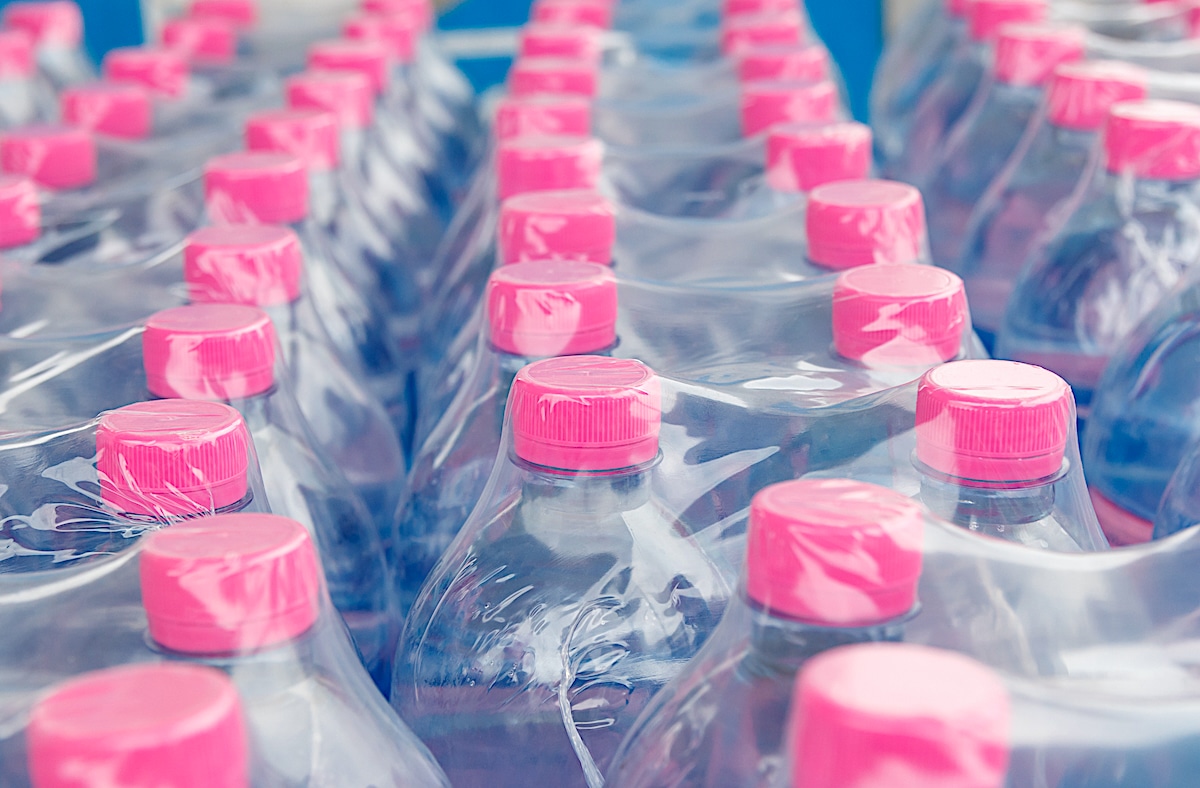 A large number of plastic beverage bottles packed in polyethylene wrap in a warehouse