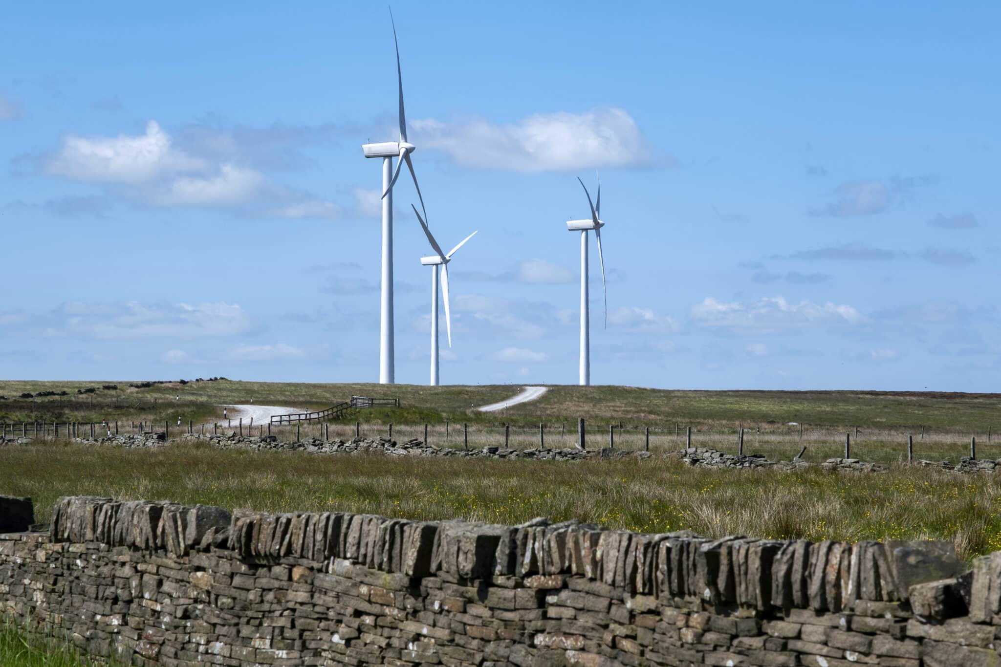 Wind turbines behind a dry stone wall on Ovenden Moor Wind Farm in West Yorkshire in Ogden near Halifax, UK