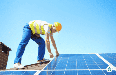 man installing solar panels on roof