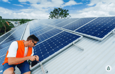 man installing solar panels on roof